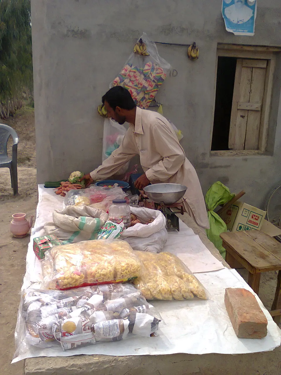 A vendor weighing goods at his small food stall